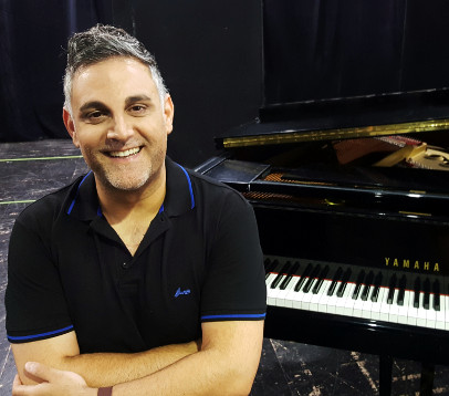 יוסף ארידן בסטודיו פונה למצלמה, ברקע פסנתר כנף