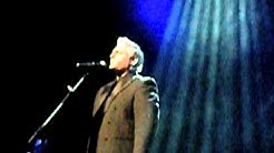 יוסף ארידן מול מקרופון בתאורת במה כחולה