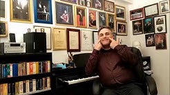 יוסף ארידן בסטודיו שבביתו ליד פסנתר, מצביע בשתי ידיו על פניו